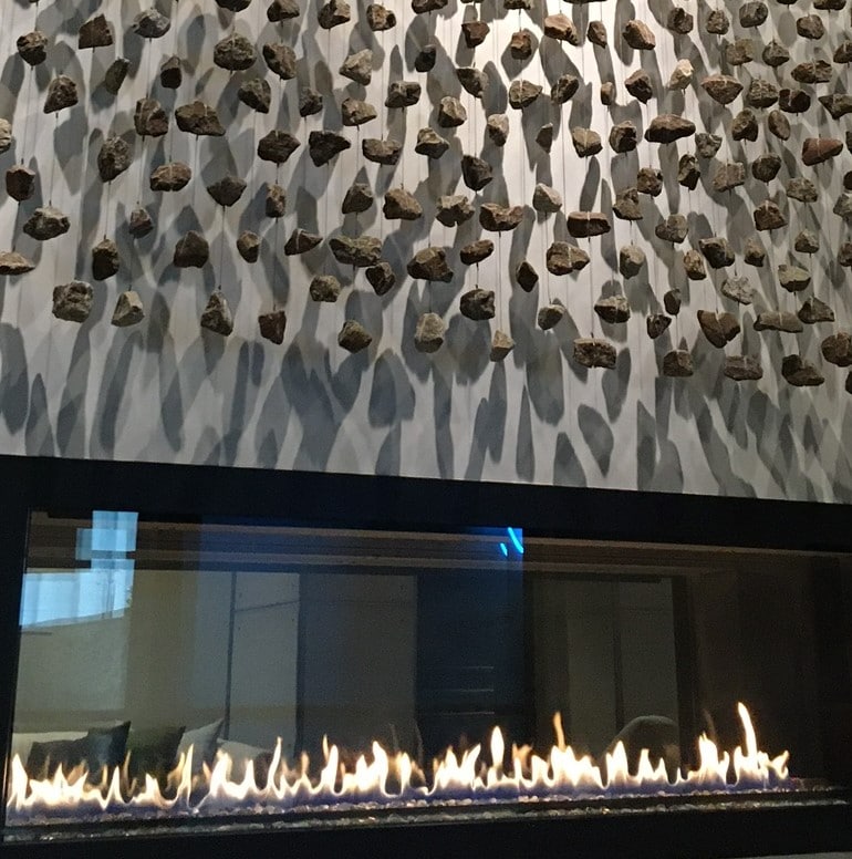 Small rocks hang along the surface of this floor-to-ceiling fireplace