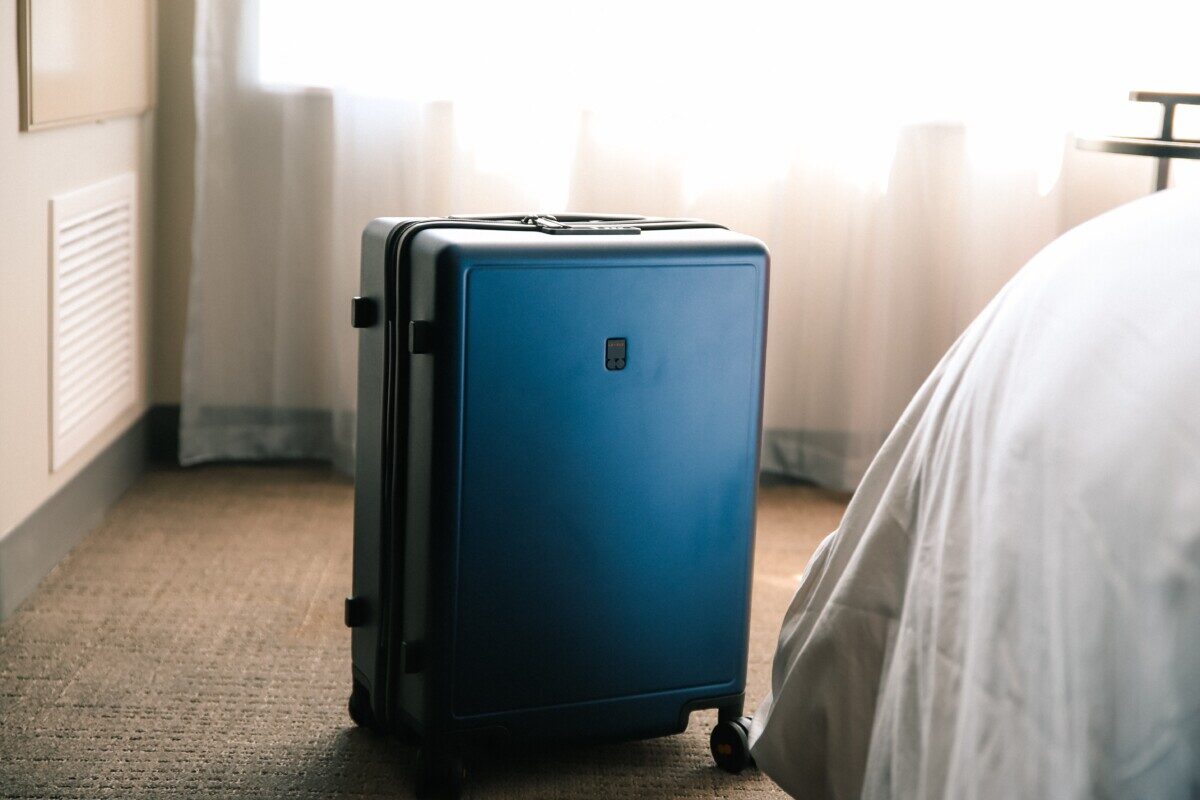 Carry on only suitcase next to bed in hotel room