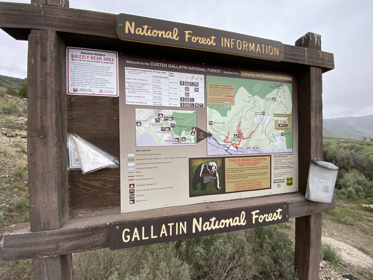 A wooden sign showing information about the Gallatin National Forest.