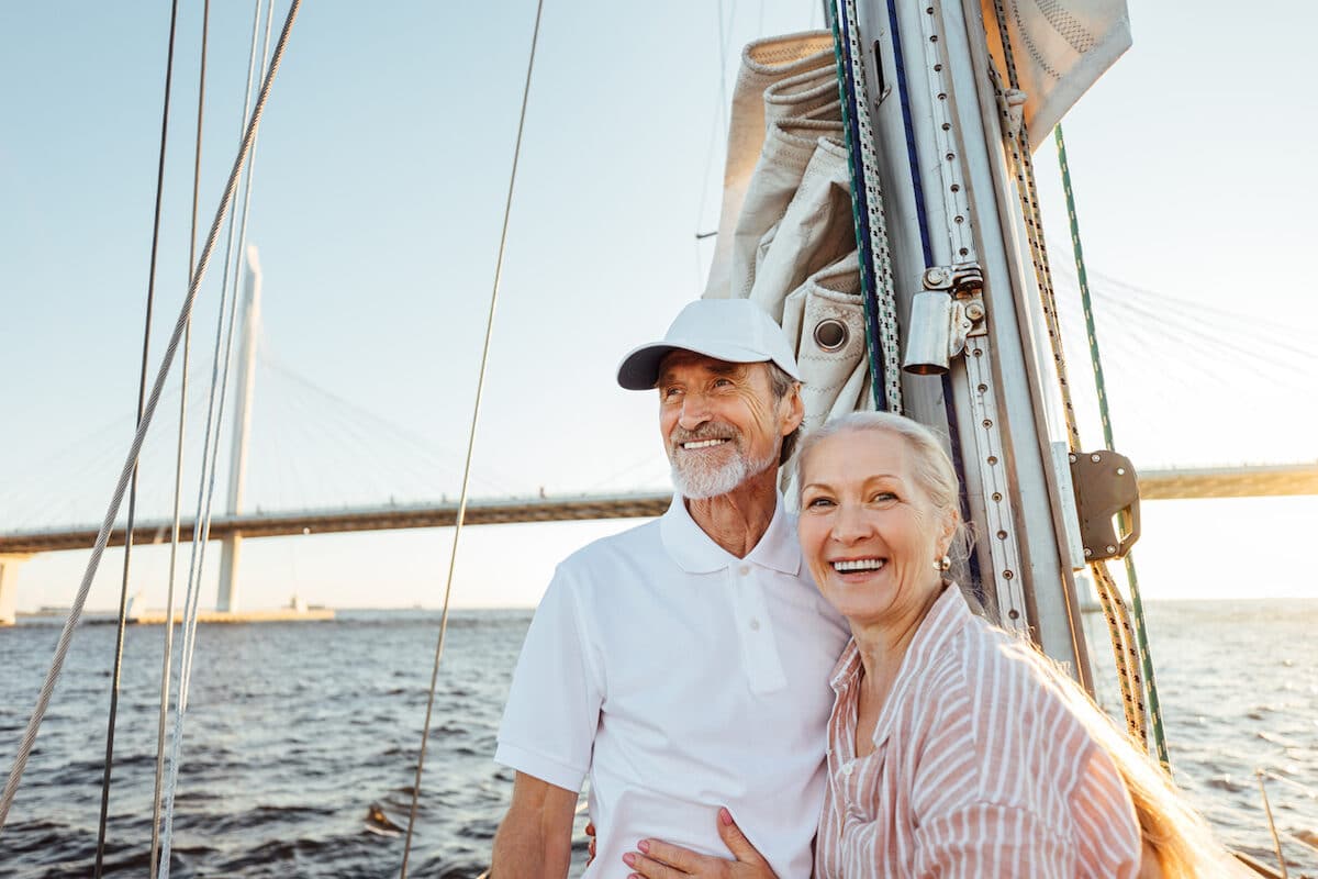 Happy senior couple standing at mast. Two smiling people enjoying boat trip.